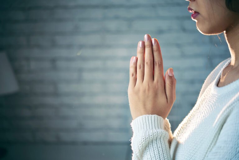 A person praying with hands clasped together, symbolizing faith and devotion.
